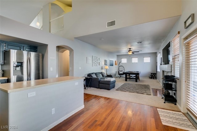 kitchen featuring stainless steel fridge, ceiling fan, blue cabinetry, wood-type flooring, and a fireplace