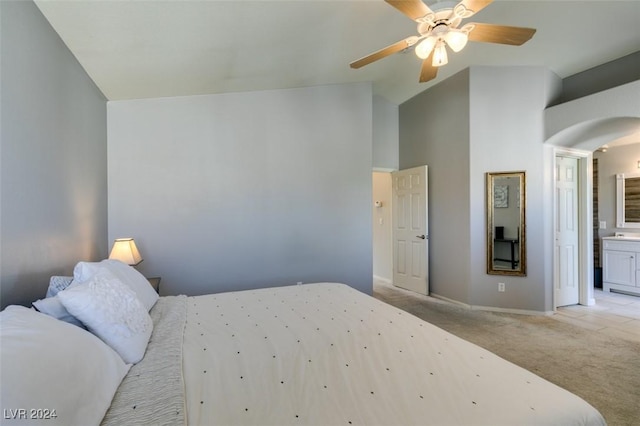 carpeted bedroom with ensuite bathroom, ceiling fan, and lofted ceiling