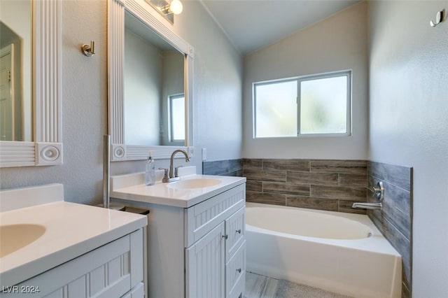 bathroom featuring a bathing tub, vanity, a healthy amount of sunlight, and vaulted ceiling