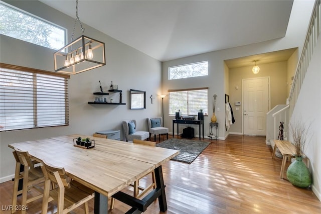 dining room with a high ceiling, hardwood / wood-style flooring, and an inviting chandelier