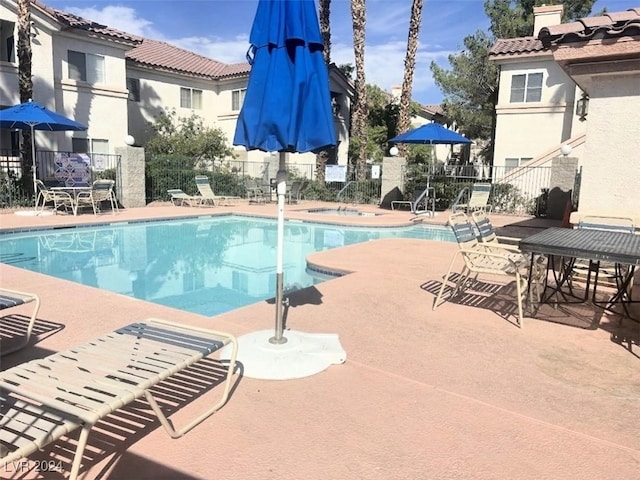 view of swimming pool featuring a hot tub and a patio area