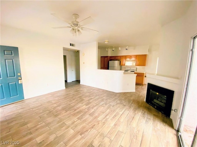 unfurnished living room with ceiling fan, rail lighting, and light hardwood / wood-style floors