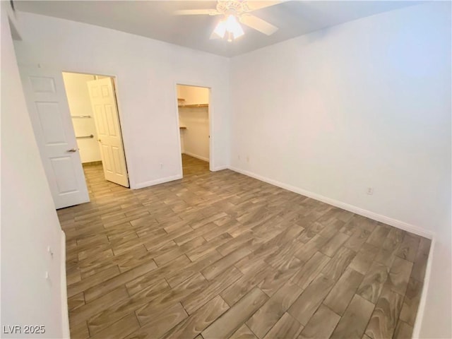 unfurnished bedroom with a walk in closet, light hardwood / wood-style flooring, a closet, and ceiling fan