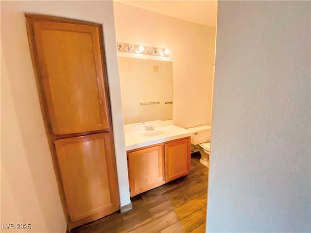 bathroom featuring wood-type flooring, vanity, and toilet