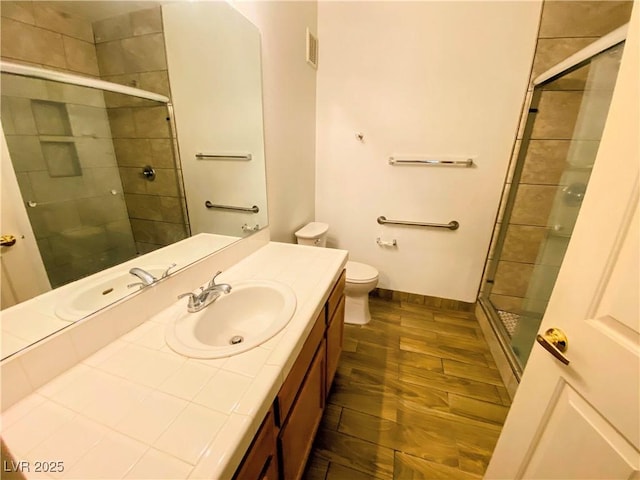 bathroom featuring vanity, an enclosed shower, hardwood / wood-style flooring, and toilet