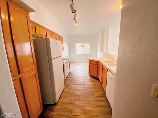 kitchen featuring sink, white appliances, an inviting chandelier, hanging light fixtures, and track lighting