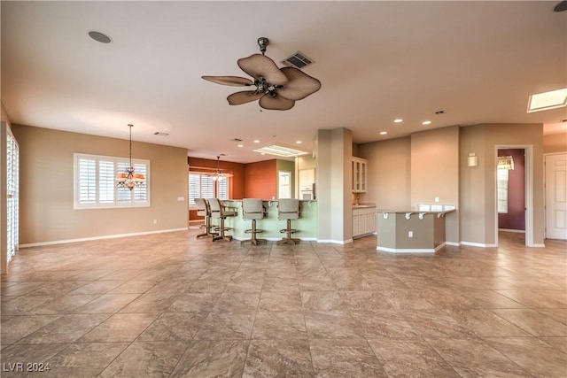 unfurnished living room featuring ceiling fan with notable chandelier