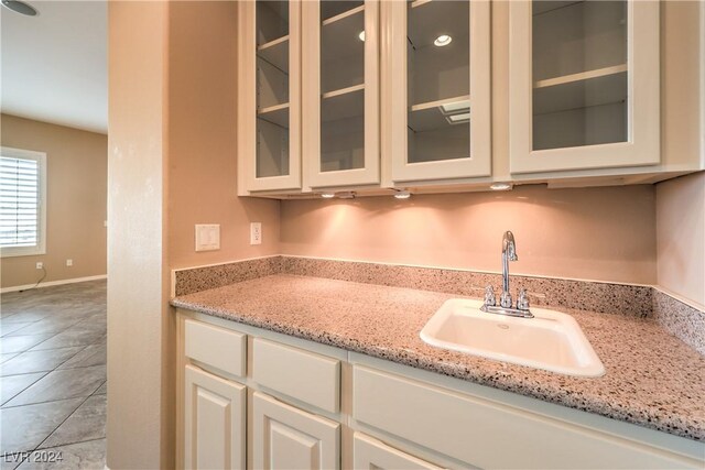 kitchen featuring light tile patterned floors, light stone counters, and sink