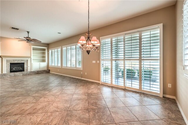 unfurnished living room with tile patterned floors, built in shelves, ceiling fan with notable chandelier, and a tile fireplace