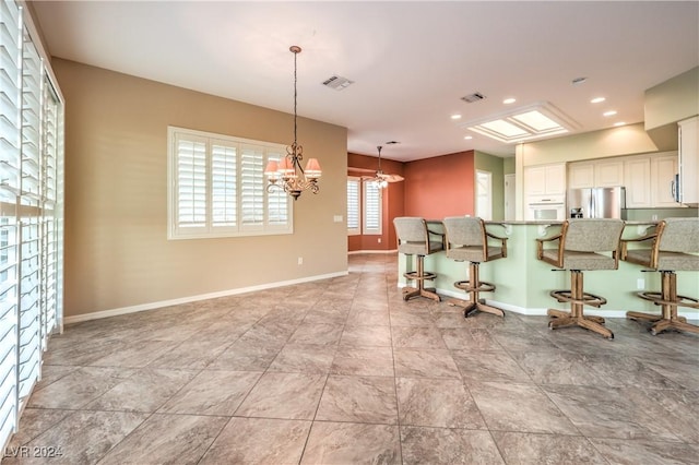 interior space featuring white cabinetry, light stone countertops, a notable chandelier, a breakfast bar, and appliances with stainless steel finishes