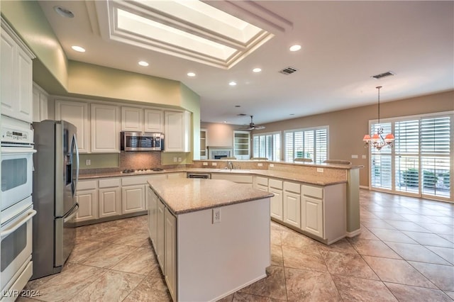 kitchen with a center island, kitchen peninsula, hanging light fixtures, and appliances with stainless steel finishes