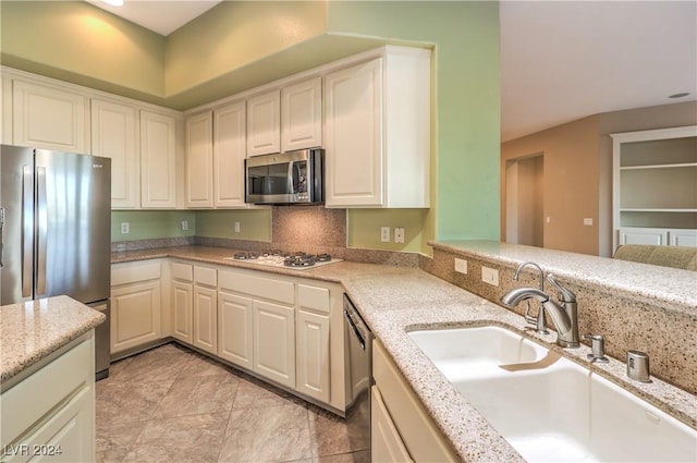 kitchen featuring light stone countertops, sink, tasteful backsplash, light tile patterned floors, and appliances with stainless steel finishes