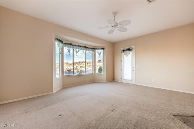 empty room featuring ceiling fan and light colored carpet