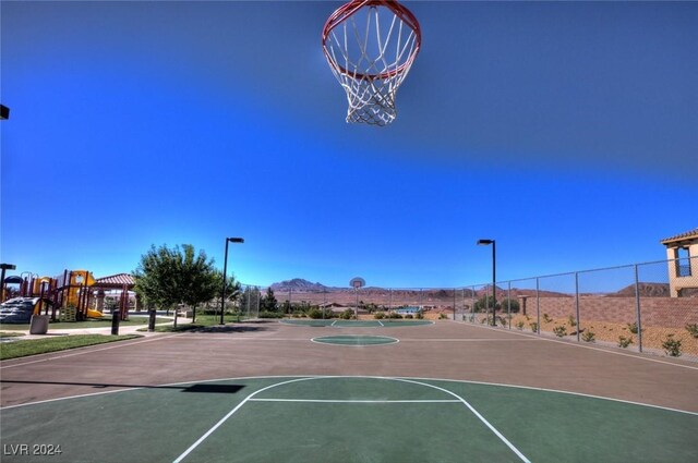 view of basketball court with a playground and a mountain view