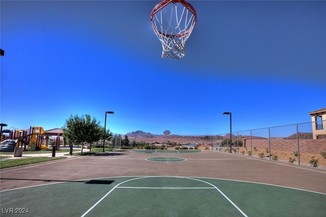 view of sport court featuring a playground and a mountain view