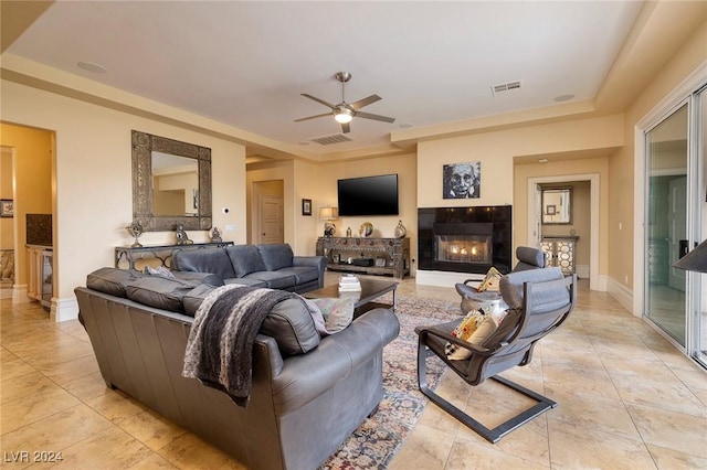 tiled living room featuring ceiling fan and a tiled fireplace