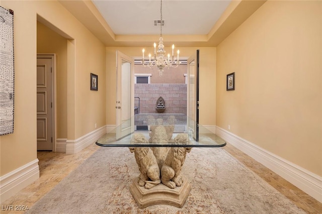 hallway featuring a chandelier and a raised ceiling