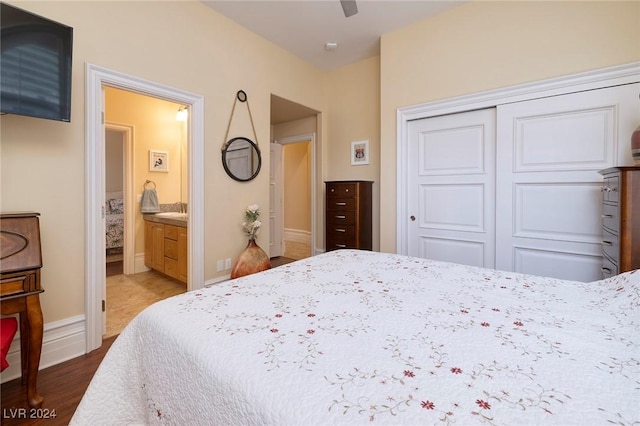 bedroom featuring connected bathroom, ceiling fan, a closet, and wood-type flooring