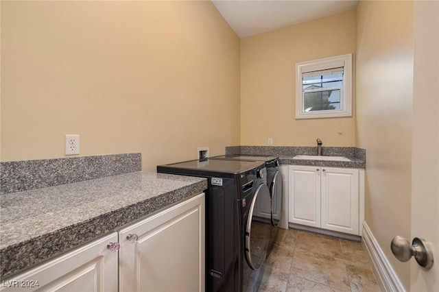 clothes washing area featuring cabinets, sink, and washing machine and clothes dryer