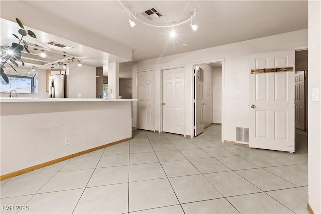 spare room featuring rail lighting, sink, and light tile patterned floors