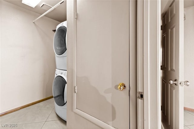 laundry area with stacked washer and clothes dryer and light tile patterned floors