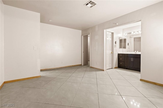 unfurnished bedroom with connected bathroom, sink, and light tile patterned flooring