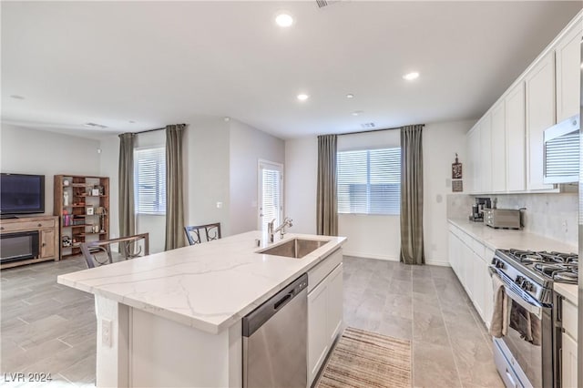 kitchen featuring white cabinetry, sink, stainless steel appliances, and a center island with sink