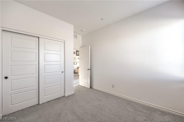 unfurnished bedroom with light carpet and a closet