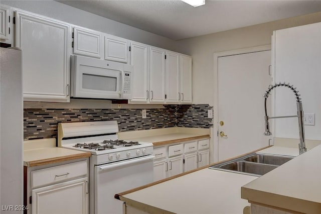 kitchen with white appliances, sink, decorative backsplash, and white cabinets