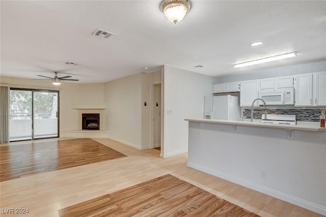 kitchen with white cabinetry, white appliances, and light hardwood / wood-style flooring