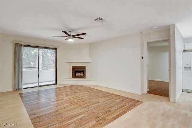 unfurnished living room featuring ceiling fan, a tile fireplace, and light hardwood / wood-style flooring