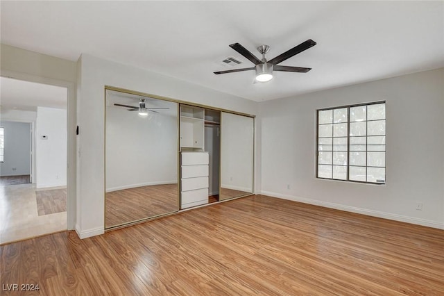 unfurnished bedroom with ceiling fan, light wood-type flooring, and a closet