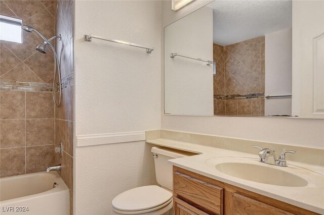 full bathroom with vanity, toilet, a textured ceiling, and tiled shower / bath