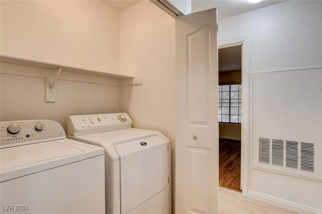 laundry room featuring washing machine and clothes dryer and light hardwood / wood-style floors