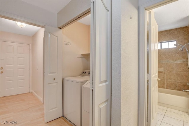 clothes washing area featuring washing machine and dryer and light wood-type flooring