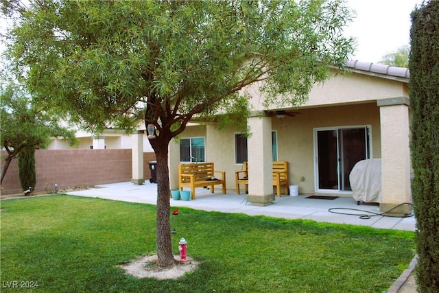 rear view of house with a patio, stucco siding, a lawn, ceiling fan, and fence