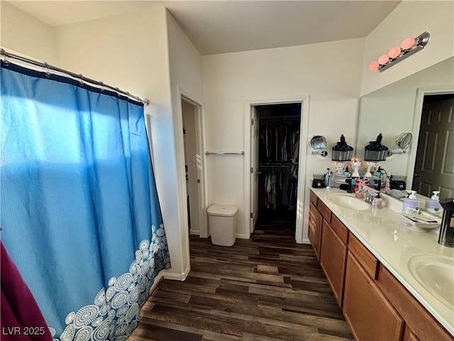 full bathroom with double vanity, a spacious closet, a shower with shower curtain, a sink, and wood finished floors