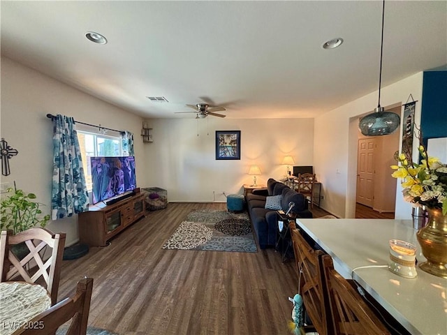 living room with dark wood-type flooring, visible vents, and a ceiling fan