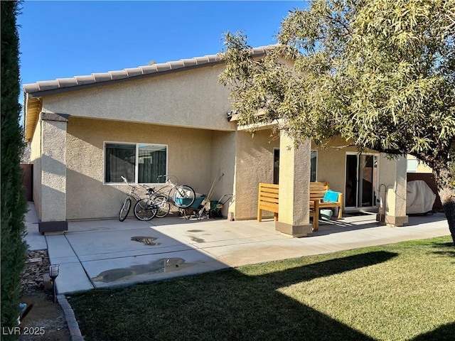 back of property featuring a yard, a patio area, a tile roof, and stucco siding