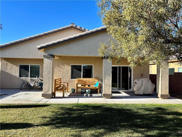 back of property featuring a lawn, a patio, and stucco siding