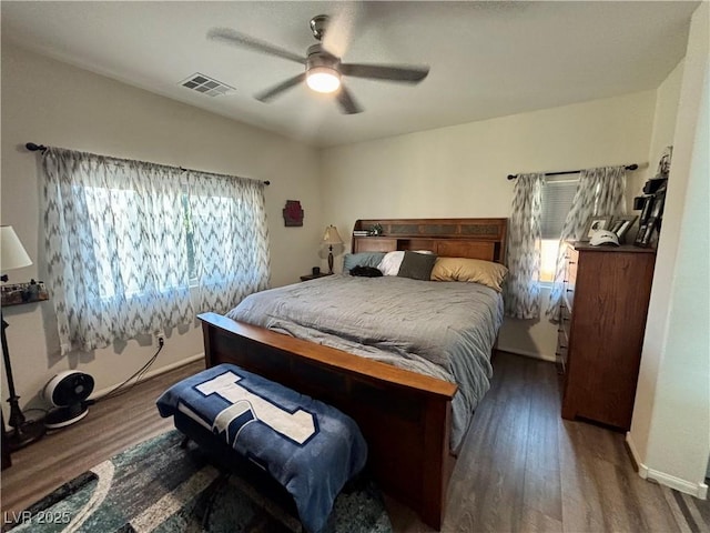 bedroom with a ceiling fan, visible vents, baseboards, and wood finished floors