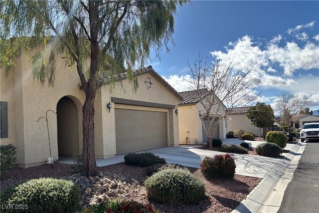 mediterranean / spanish-style home featuring driveway, an attached garage, a tile roof, and stucco siding