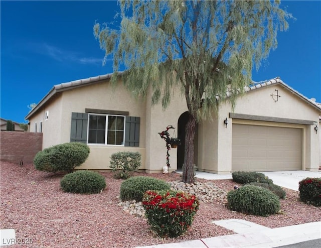 view of front of property featuring a tiled roof, an attached garage, fence, and stucco siding