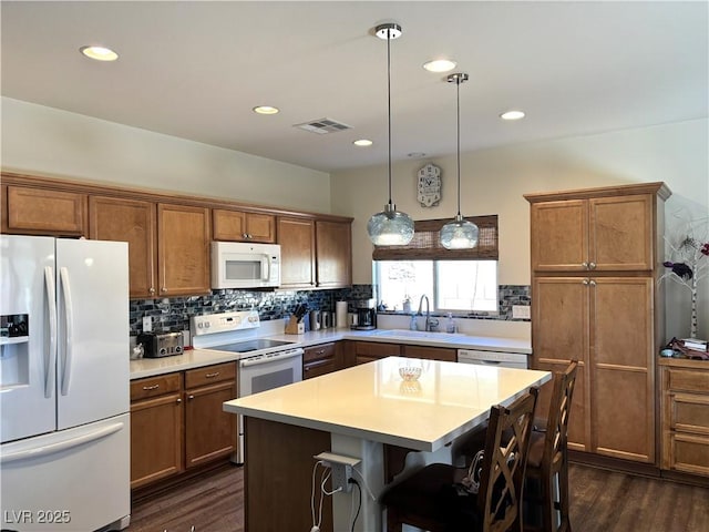 kitchen with white appliances, backsplash, a sink, and brown cabinets