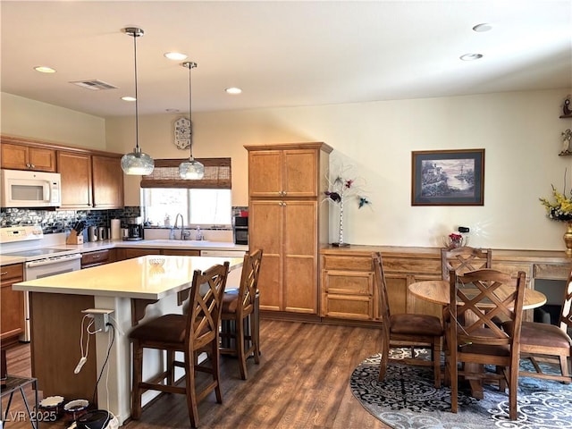 kitchen featuring white appliances, visible vents, dark wood-style floors, light countertops, and a sink