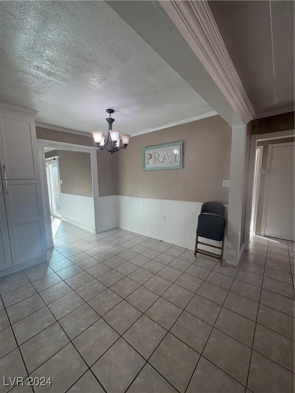 spare room with ornamental molding, a textured ceiling, light tile patterned floors, and a chandelier