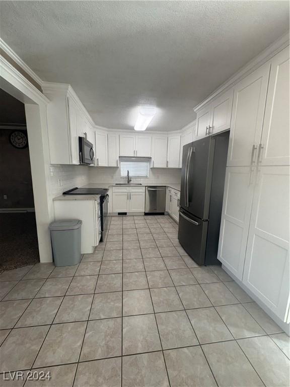 kitchen with white cabinets, light tile patterned floors, sink, and appliances with stainless steel finishes