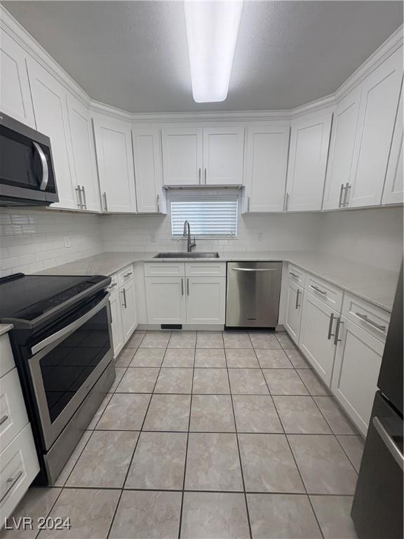 kitchen with light tile patterned flooring, white cabinetry, sink, and appliances with stainless steel finishes