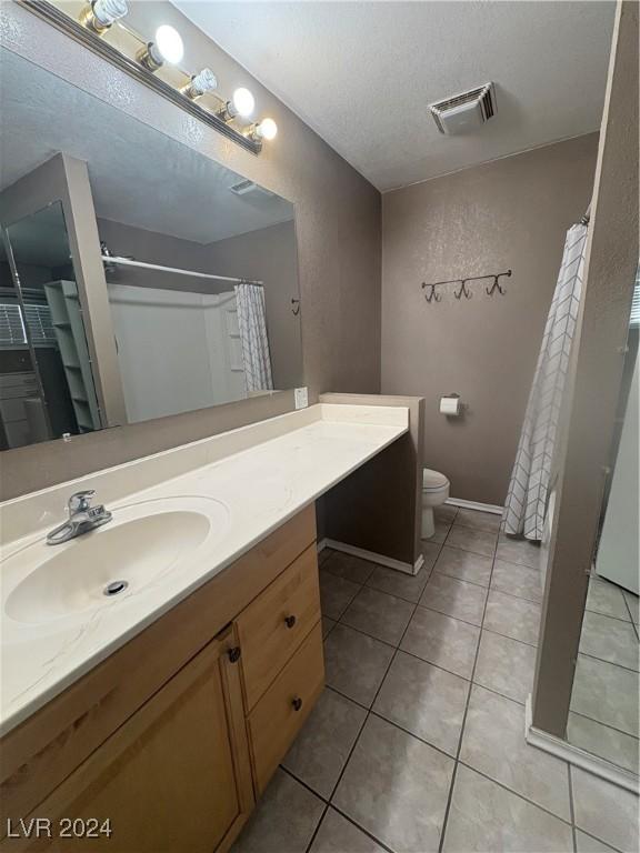 bathroom with tile patterned floors, vanity, a textured ceiling, and toilet