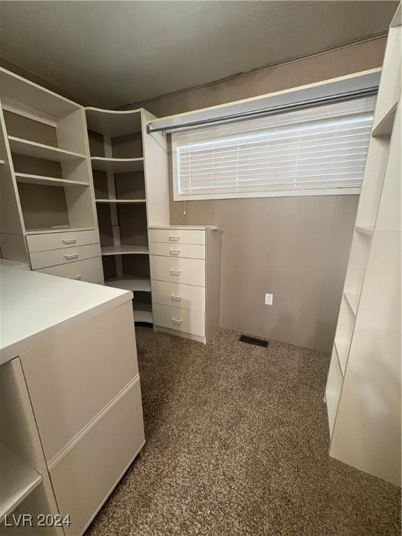 walk in closet featuring dark carpet